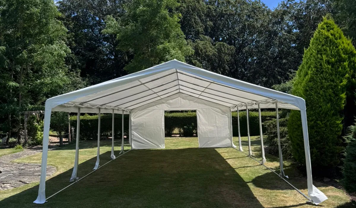 Marquee with open sides and solid end panels on a garden lawn in summer